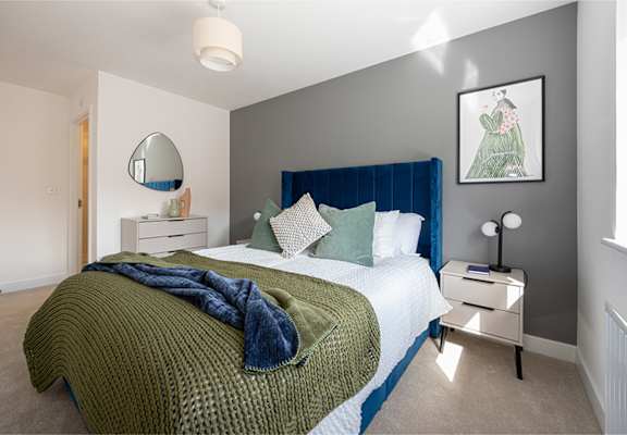 A bedroom with a bed, nightstand, and a mirror on the wall.
