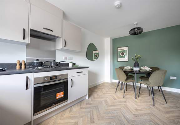 A kitchen with a stove top oven and a dining table with chairs.