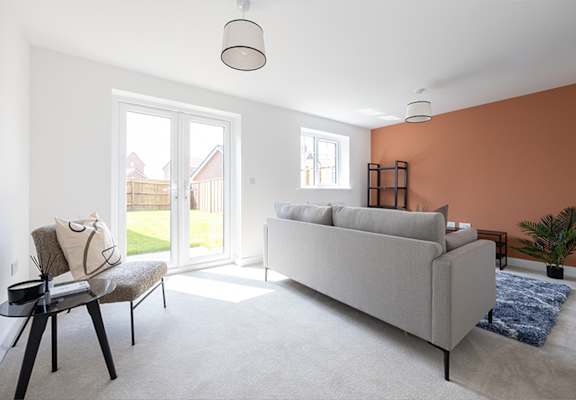 A living room with a grey couch, a chair, a small table, and a window.