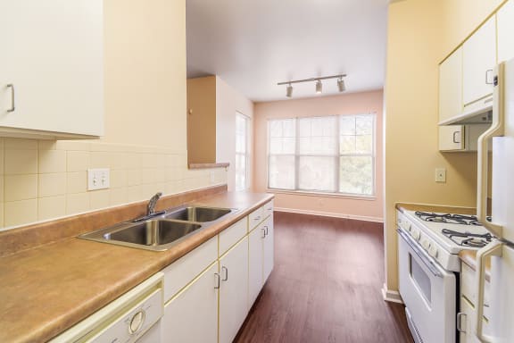 an empty kitchen with white appliances and wooden floors