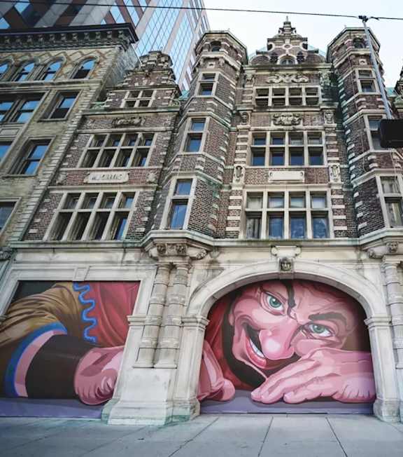 A mural of a man's face is painted on the side of a building.