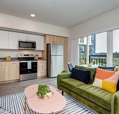 a living room with a green couch and a kitchen at Hazel Apartments, Washington