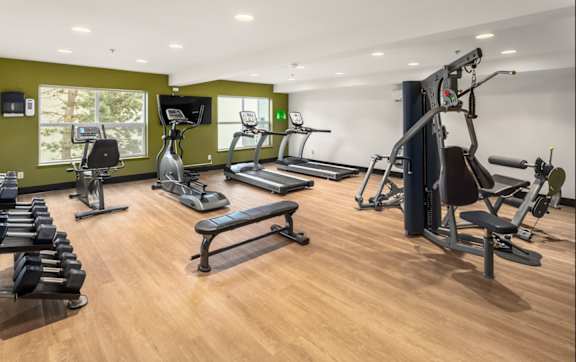 A gym with a variety of equipment including treadmills, weights, and exercise machines.