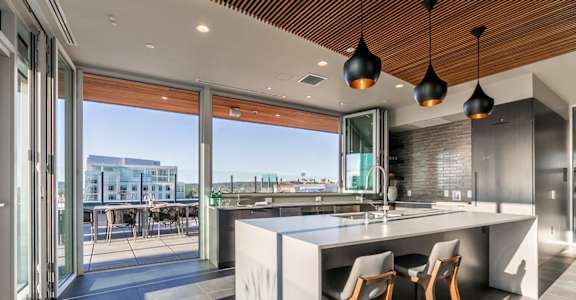 A modern kitchen with a large island and wooden ceiling.