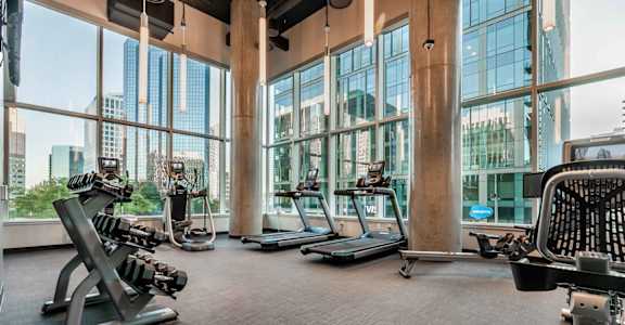 A gym with a view of the city outside the large windows.