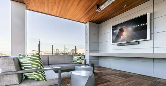 A modern living room with a grey sofa and a television on the wall.
