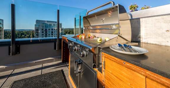 A modern outdoor kitchen with a grill and a table set for two.