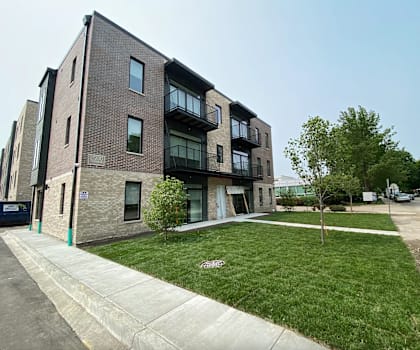 A modern brick apartment building with a green lawn in front.