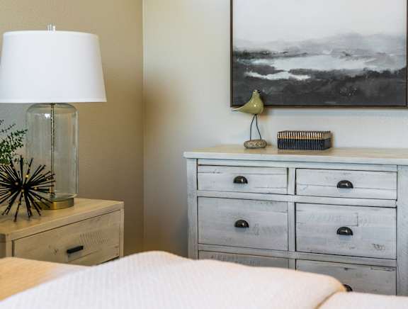 A bedroom with a bed, nightstand, and a large picture on the wall.