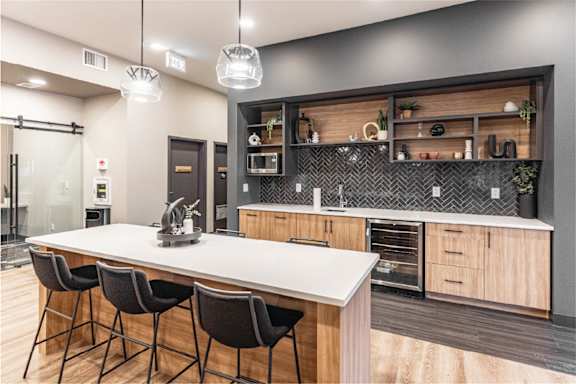 A modern kitchen with a white countertop and black bar stools.at Podium Apartments, Calgary, AB