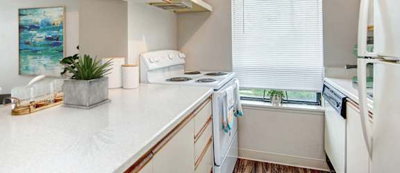 A white kitchen with a white fridge and a white counter top.