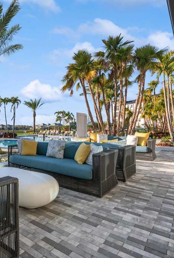 A patio with a couch and chairs with a view of palm trees.