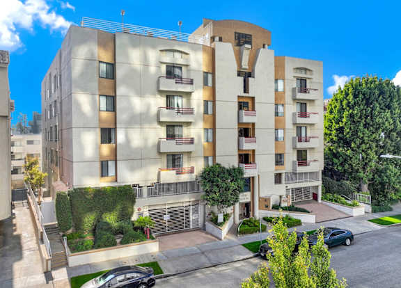 Exterior aerial view of an apartment building with cars parked.