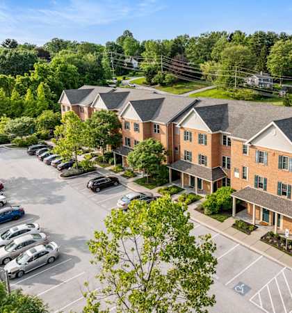 A parking lot in front of a building with cars parked.