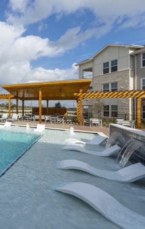 a large swimming pool with lounge chairs and a yellow pavilion in the background