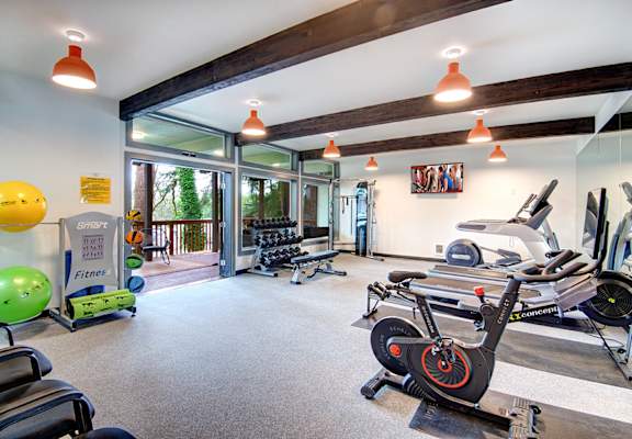 A gym with a variety of exercise equipment including treadmills, stationary bikes, and weights.