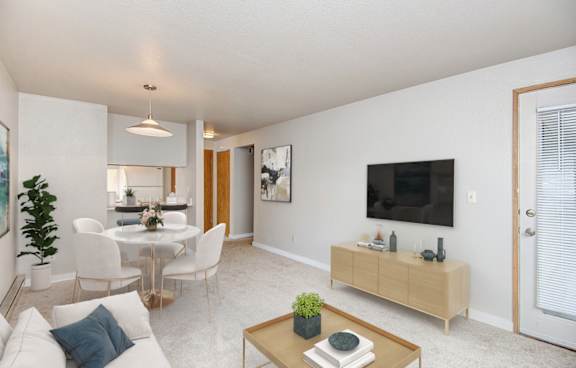 A living room with a white couch, a coffee table, and a television.