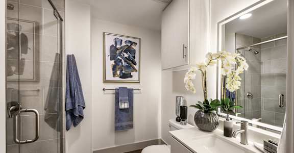 a bathroom with a shower and a sink and a vase of flowers