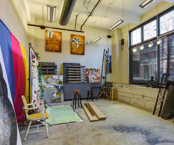 A room with a lot of art supplies and a large window.