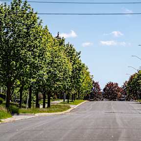 A row of townhouses with a car parked in front of the first one.