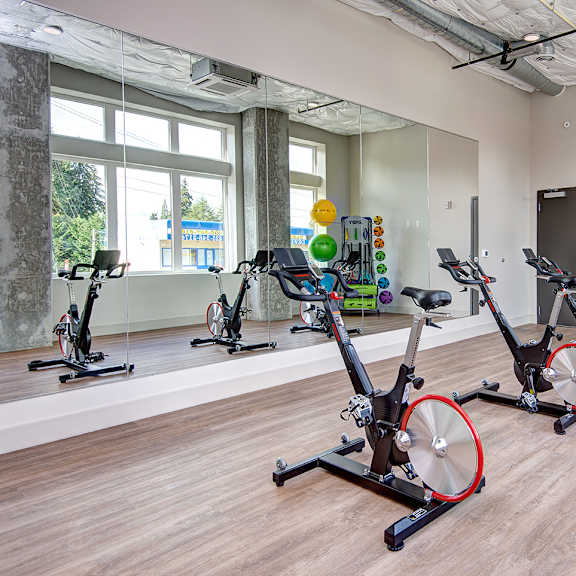 a fitness room with exercise bikes and weights at the belgard apartments