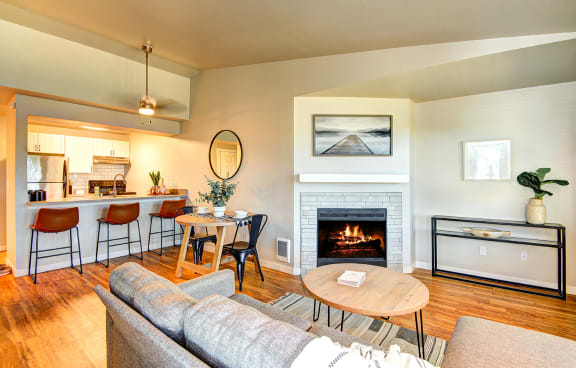 a living room with a fireplace and a table with chairs at The Lynx Apartments, Everett, WA, 98204