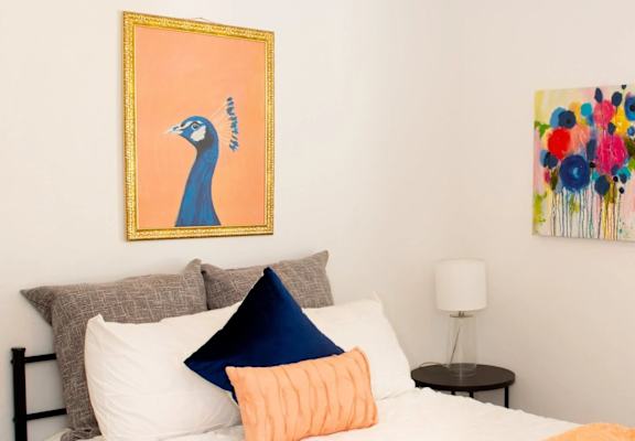 a bedroom with a white bed and a painting on the wall