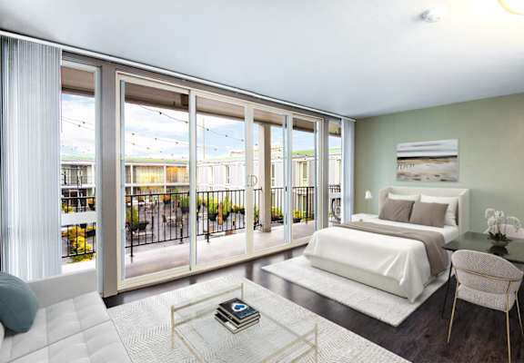 A bedroom with a large bed and a balcony with a view of the outside.