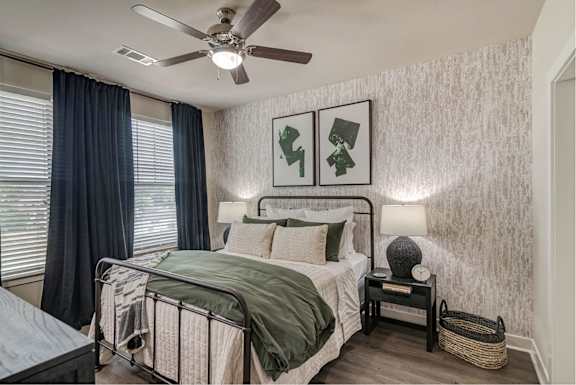 A bedroom with a bed, nightstand, and two pictures on the wall.