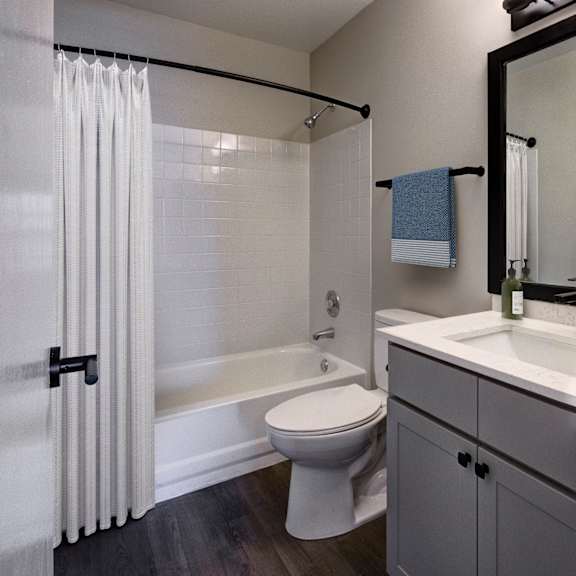 A white toilet sits in a bathroom next to a bathtub.