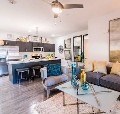 A living room with a coffee table and couch and chairs and island and microwave and stove and oven
