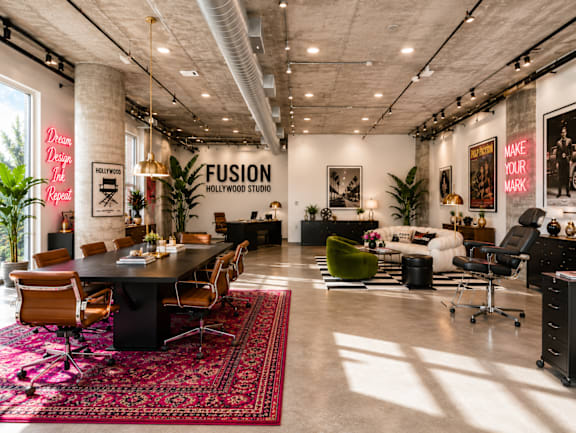 A modern live/work office space with a large table and chairs, a couch, and a rug at Fusion Hollywood.
