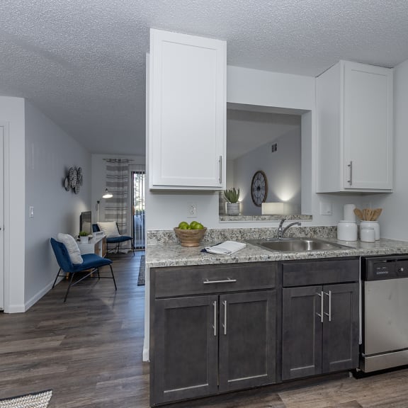 an open kitchen and living room with white cabinets and a sink