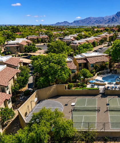 A tennis court is surrounded by houses and trees.