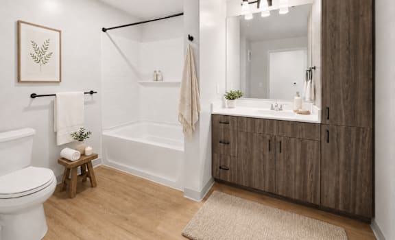 A bathroom with a white toilet, a white bathtub, a wooden cabinet, and a mirror.