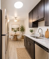 A kitchen with a refrigerator, sink, and dining table.