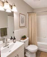 A white bathroom with a toilet, sink, and shower.