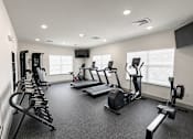 Thumbnail 2 of 10 - A spacious gym with treadmills, elliptical machines, and dumbbells.
