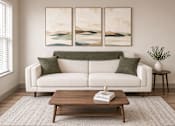 Thumbnail 6 of 10 - A living room with a white couch, a coffee table, and two paintings on the wall.