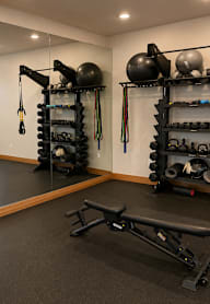 A home gym with a bench, weights, and exercise equipment.
