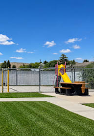 A playground with a slide and a fence in the background.