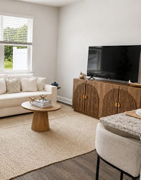 A dining room with a table set for two and a grey sofa.