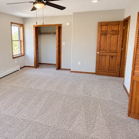 A room with a ceiling fan and a doorway leading to another room.