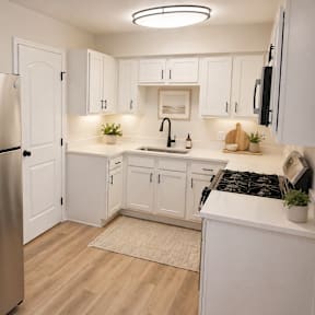 A modern kitchen with a stainless steel refrigerator and white cabinets.