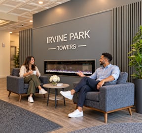 Two people are sitting in a waiting area with a sign that says Irvine Park Towers.