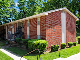 A red brick apartment building with a green lawn in front.