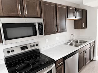 A modern kitchen with dark brown cabinets and stainless steel appliances.
