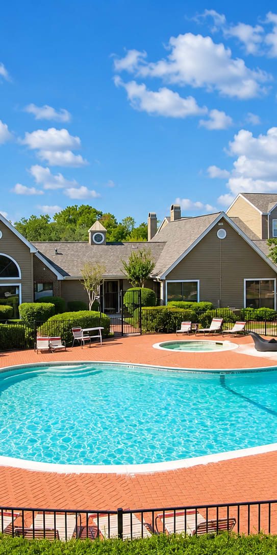 A swimming pool surrounded by a black fence and lounge chairs.