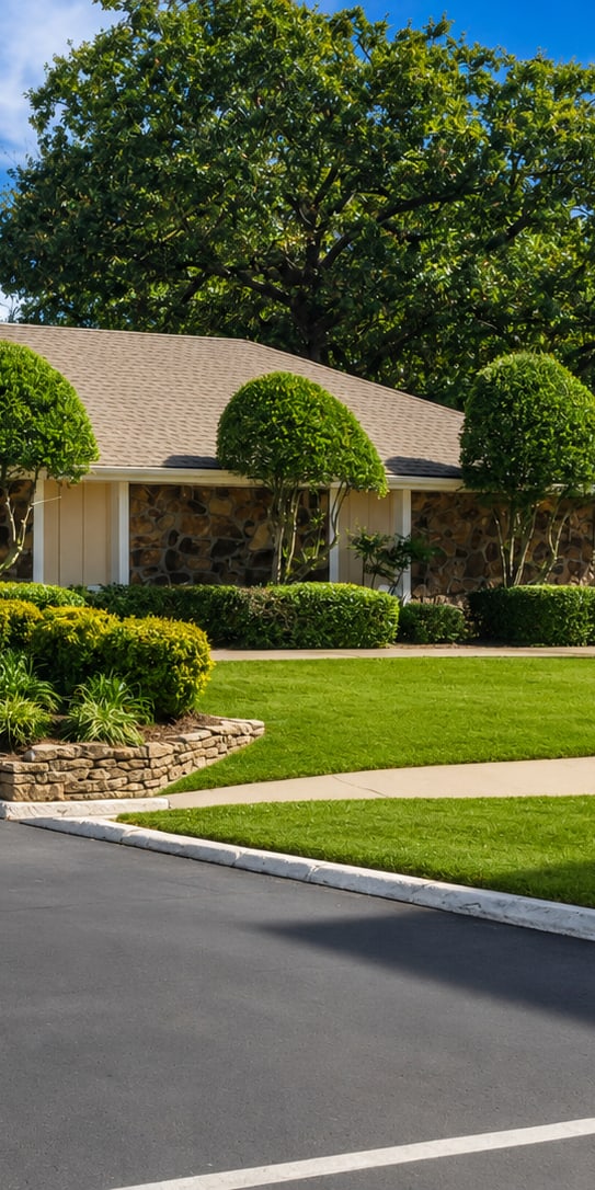 A house with a grey roof and a white door is surrounded by greenery.