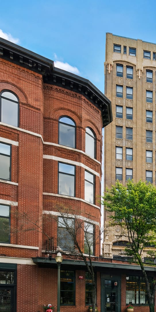 A large building with many windows sits in the middle of a city street.